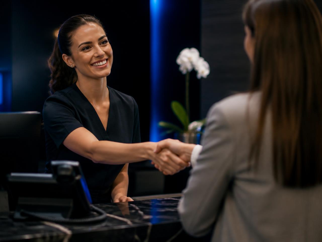 Receptionist greeting a customer warmly at a modern front desk